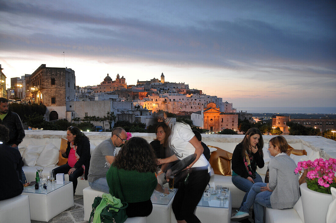 Old town of Ostuni in the evening light with cafe, Apulia, Italy