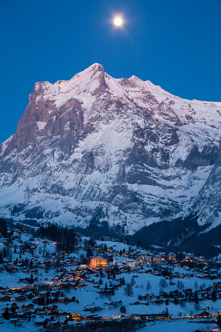 Abendstimmung und Vollmond über Grindelwald, dahinter das Wetterhorn, Wintersportort in der Jungfrauregion, Berner Oberland, Kanton Bern, Schweiz, Europa