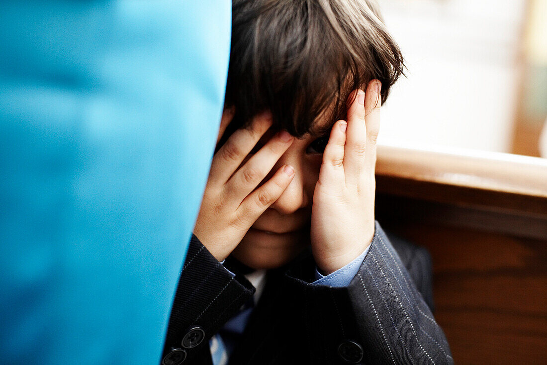 Young Boy in Suit Covering Eyes