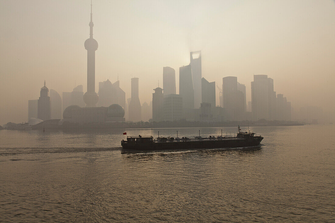 Skyline of Pudong and freighter on Huangpu River at dawn, Pudong, Shanghai, China, Asia