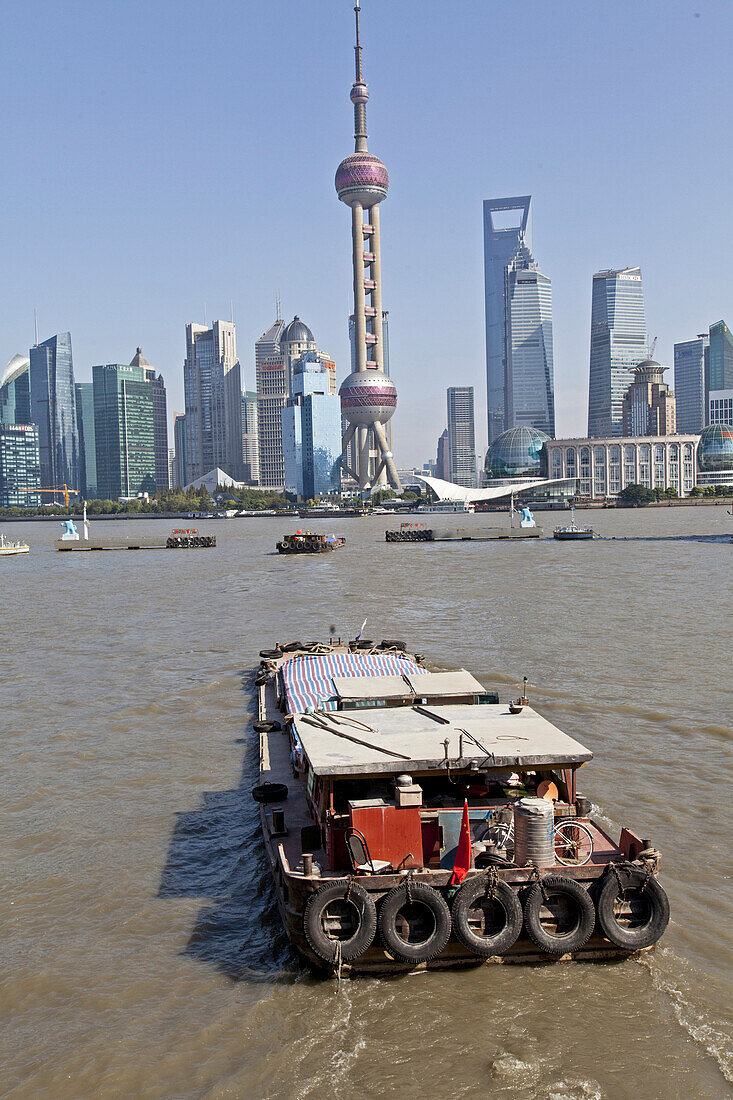 Barge crossing Huangpu river in front of Pudong skyline, Shanghai, China, Asia