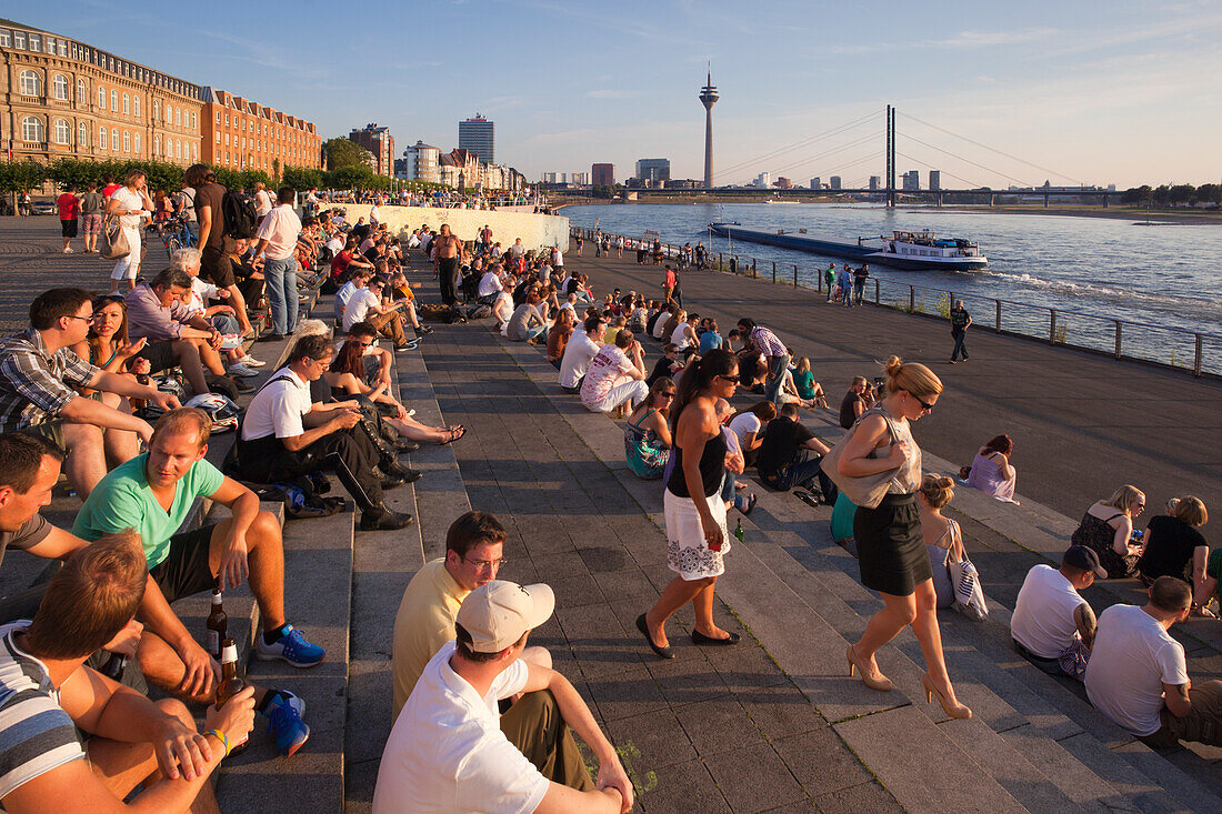 People sitting on the stairs to the Rhine river promenade, Duesseldorf, North Rhine-Westphalia, Germany, Europe