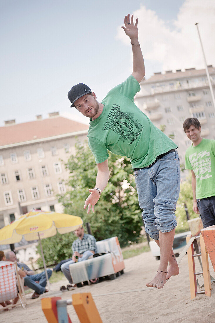 Junger Mann balanciert am Donaustrand auf einer Slackline, Wien, Österreich, Europa