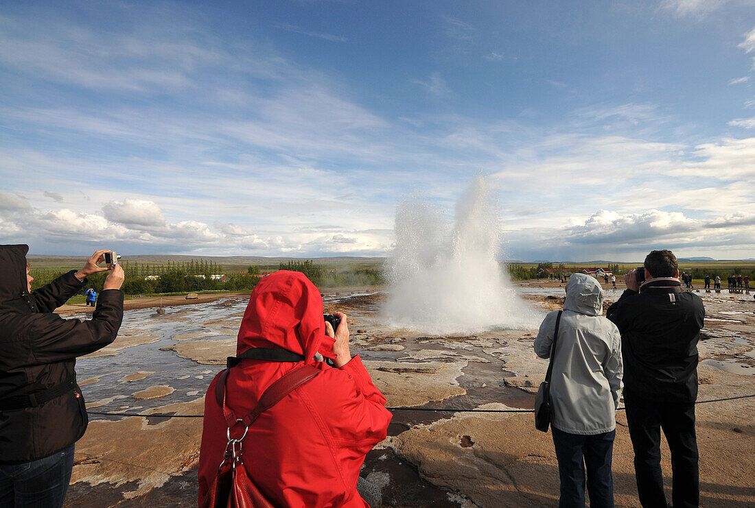 Tourists taking photos of the Strokkur geyser in the valley of Haukadalur at the golden circle, Iceland, Europe