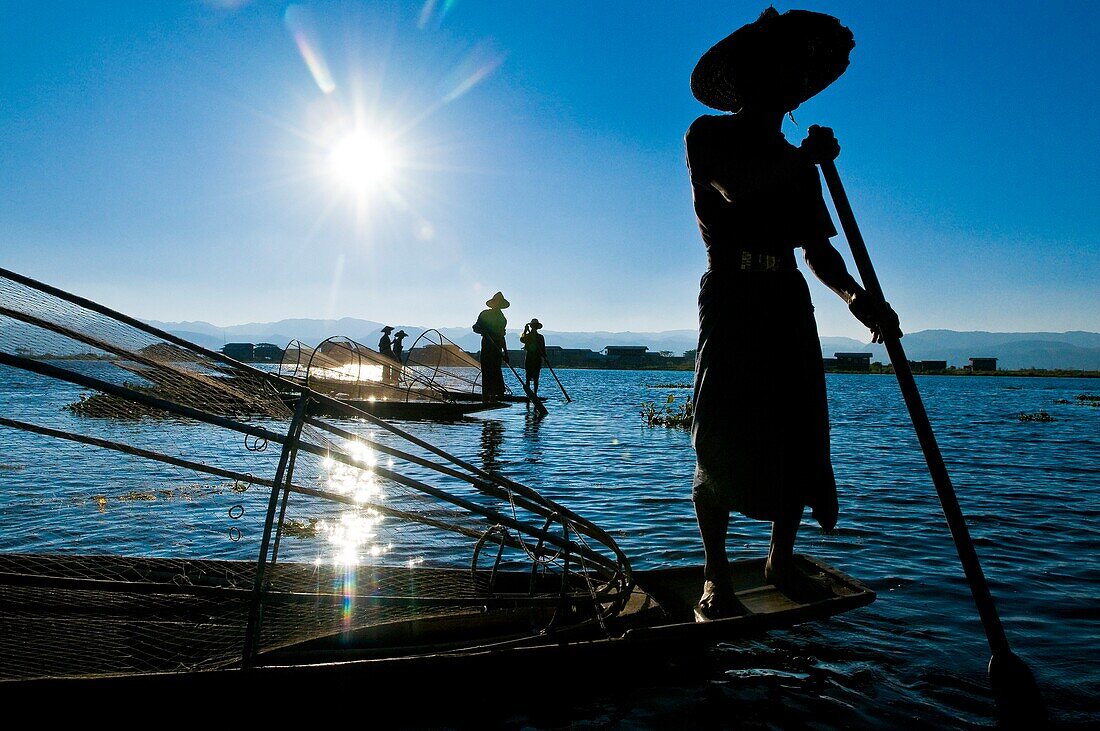 Myanmar (Burma), Shan State, Inle lake, Intha fishermen have created an unique way to move on the water : standing up on a leg at the back of a canoe, they lean the other on a stick that they guide with their ankle, the foot behind, thanks to their keepne