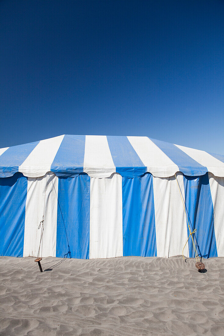 A large blue and white striped tent or marquee, on the sand at a beach festival in Long Beach, Washington USA., Large event tent at beach