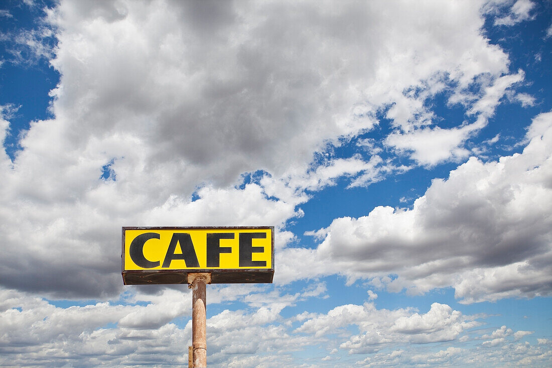Road sign in large black lettering on a yellow background. Wikieup, Arizona, USA. Clouds gathering in sky., Cafe sign against cloud filled sky