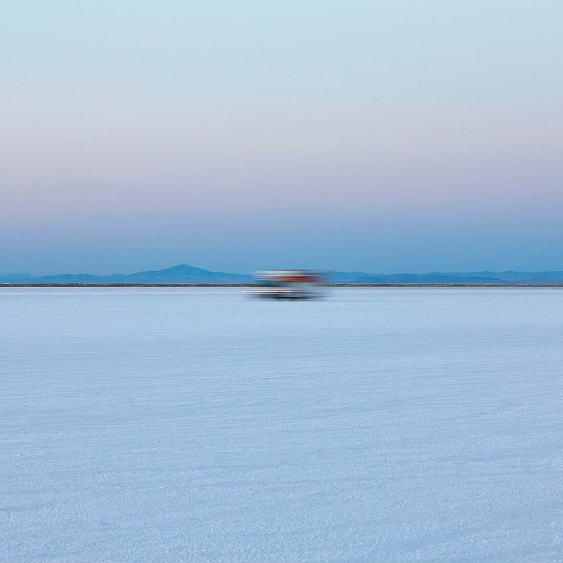 Truck driving on salt flats at dawn during Speed Week, an annual amateur auto racing event on the Bonneville Salt Flats., Bonneville Salt Flats Speed Week auto racing event