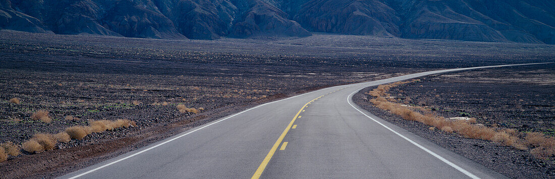 A highway curving through desolate area of Death Valley National Park, California, Highway in Death Valley National Park