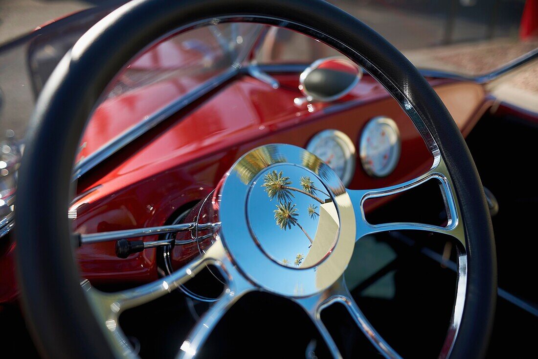 palm trees reflected in the steering wheel of a vintage automobile