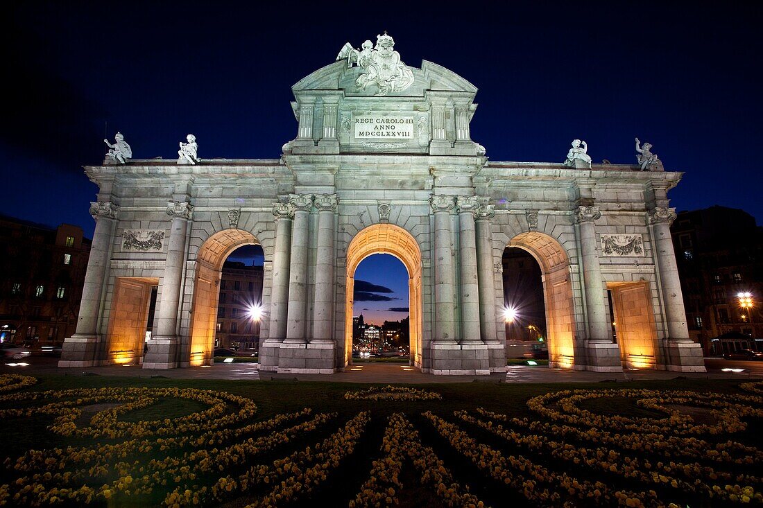Night time view of the historic Puerta de Alcalá monument in the Plaza de la Independencia Madrid Spain
