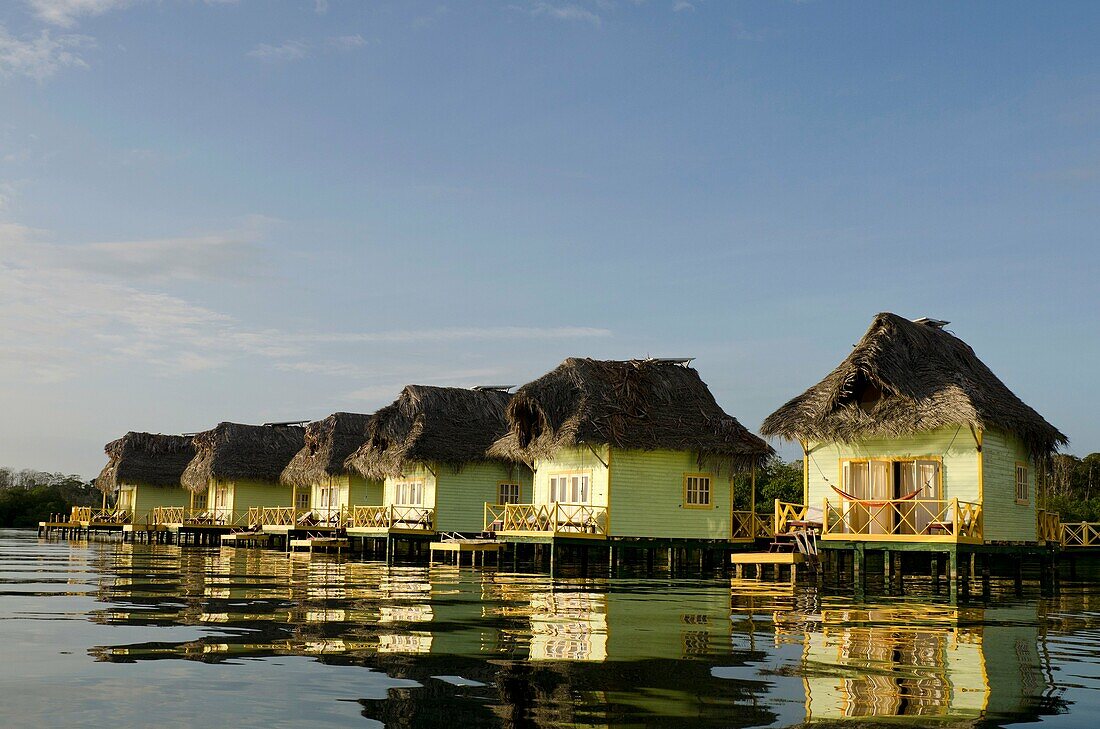 Thatch roofed bungalows on stilts in lagoon at Colon Island  Punta Caracol Hotel, Bocas del Toro, Panama, Caribbean, Central America
