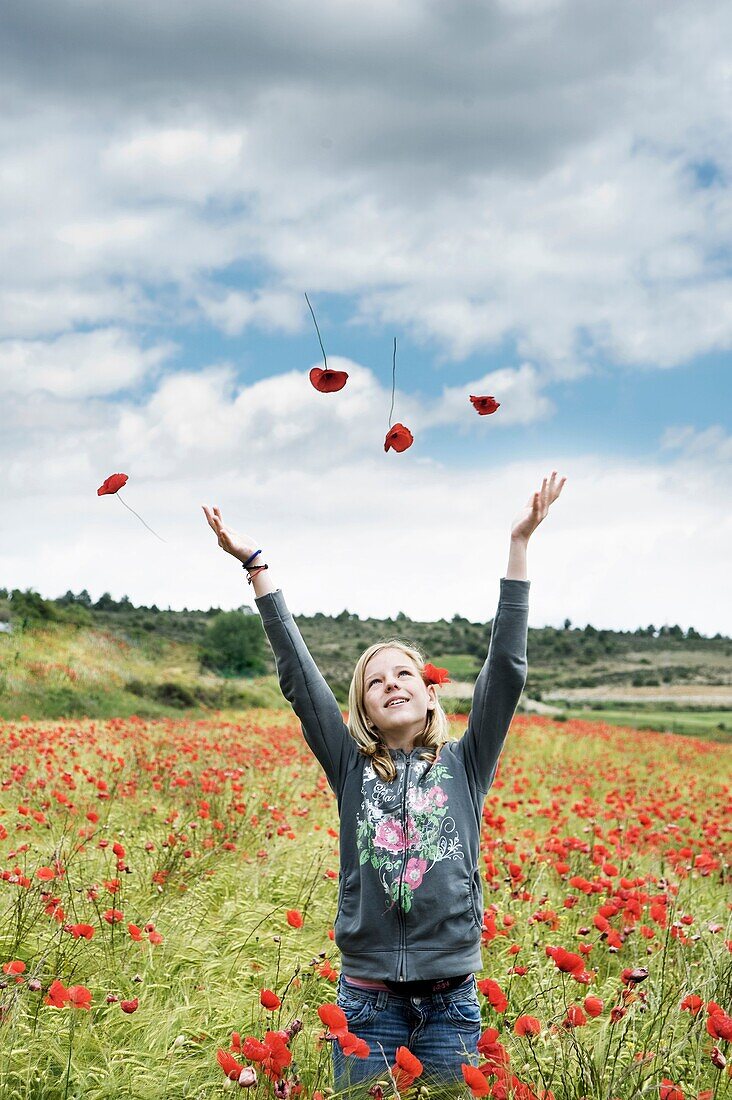 Blonde teen girl throwing flowers in the wind.