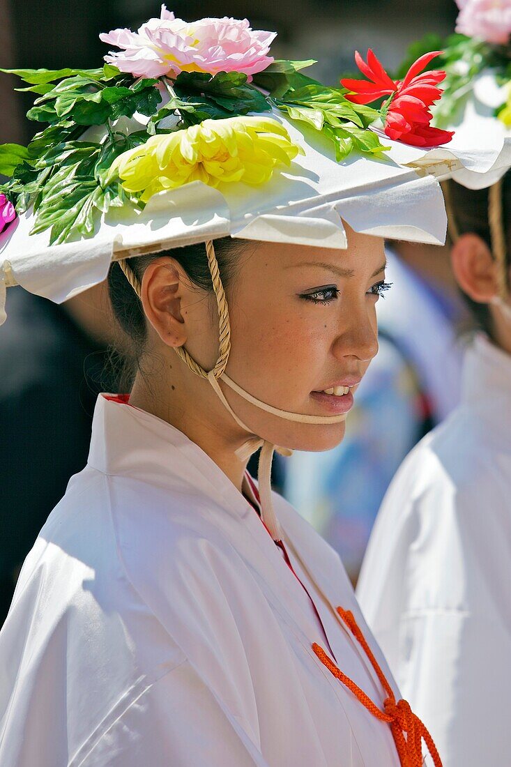 A costumed woman wearing a flower decorated hat waiting for the parade to start