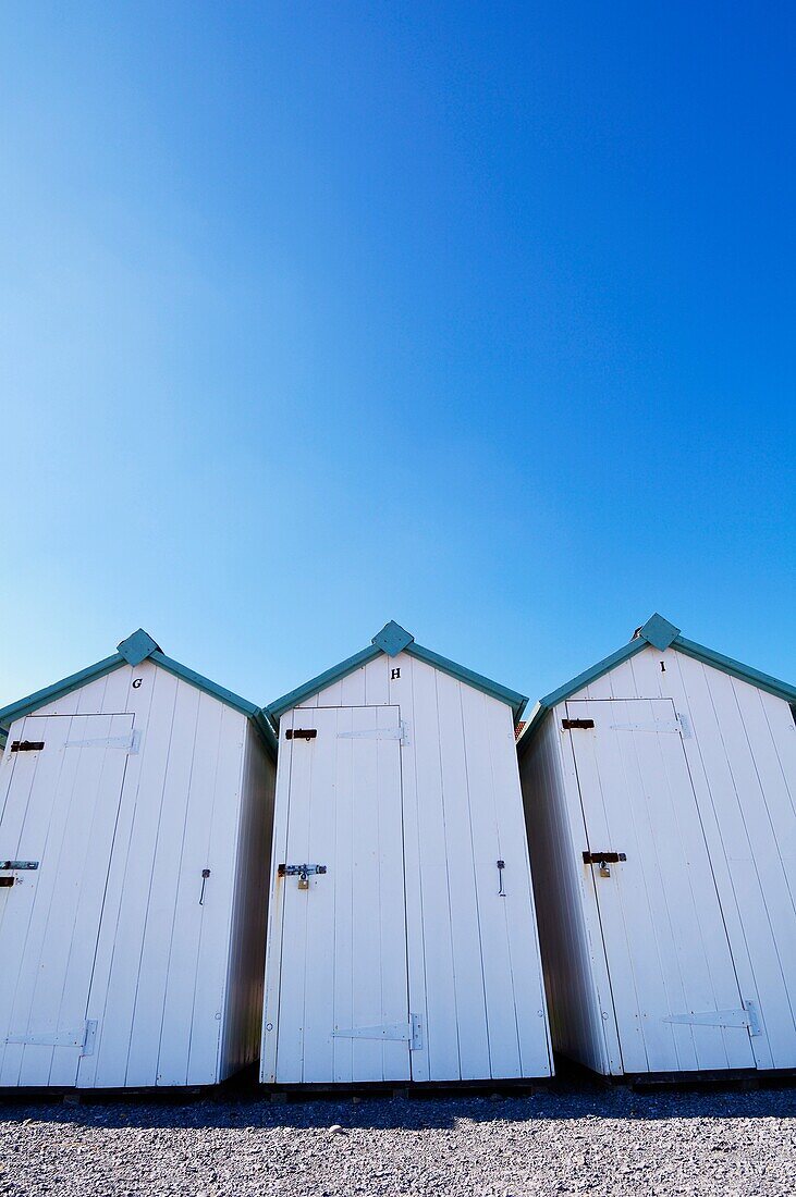 White beach huts under a clear blue sky at Budleigh Salterton, Devon, England, United Kingdom