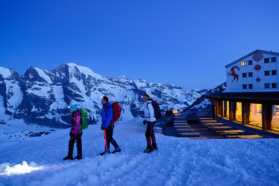 Three mountaineers starting from illuminated hut Diavolezza to Piz Palue, Diavolezza, Grisons, Switzerland