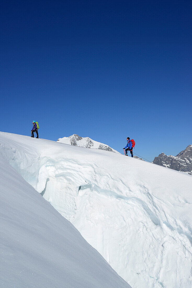 Zwei Bergsteiger steigen vor Gletscherspalte zum Piz Palü auf, Graubünden, Schweiz