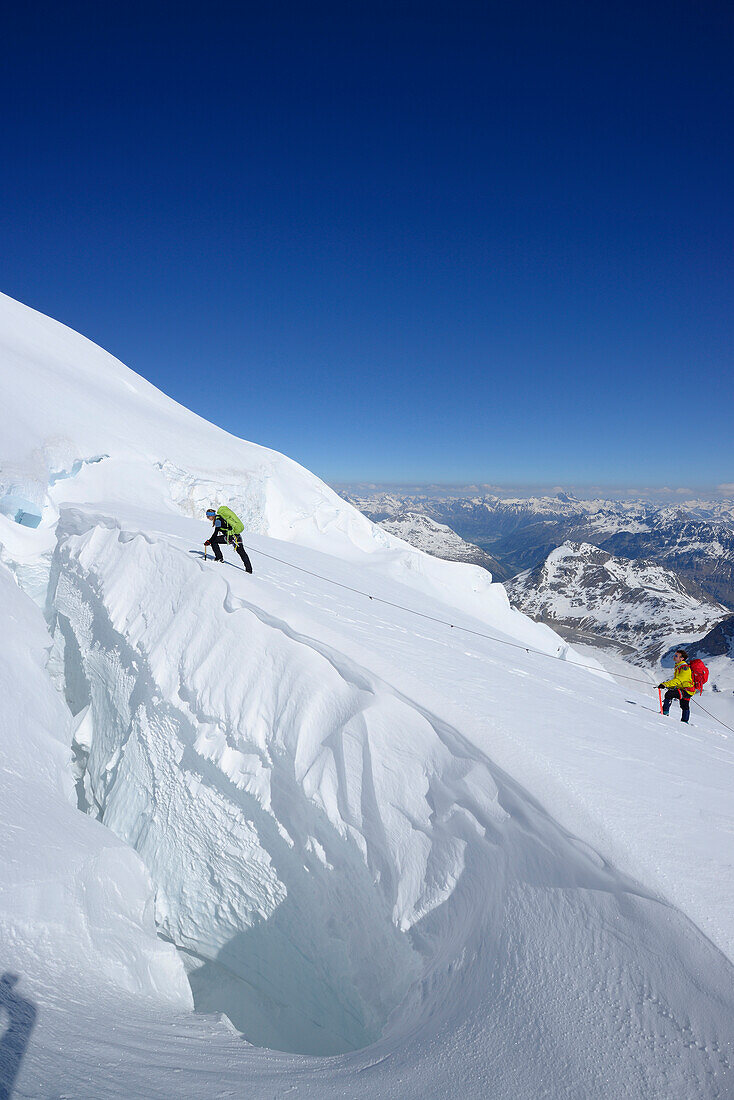 Zwei Bergsteiger überqueren große Gletscherspalte, Piz Palü, Graubünden, Schweiz