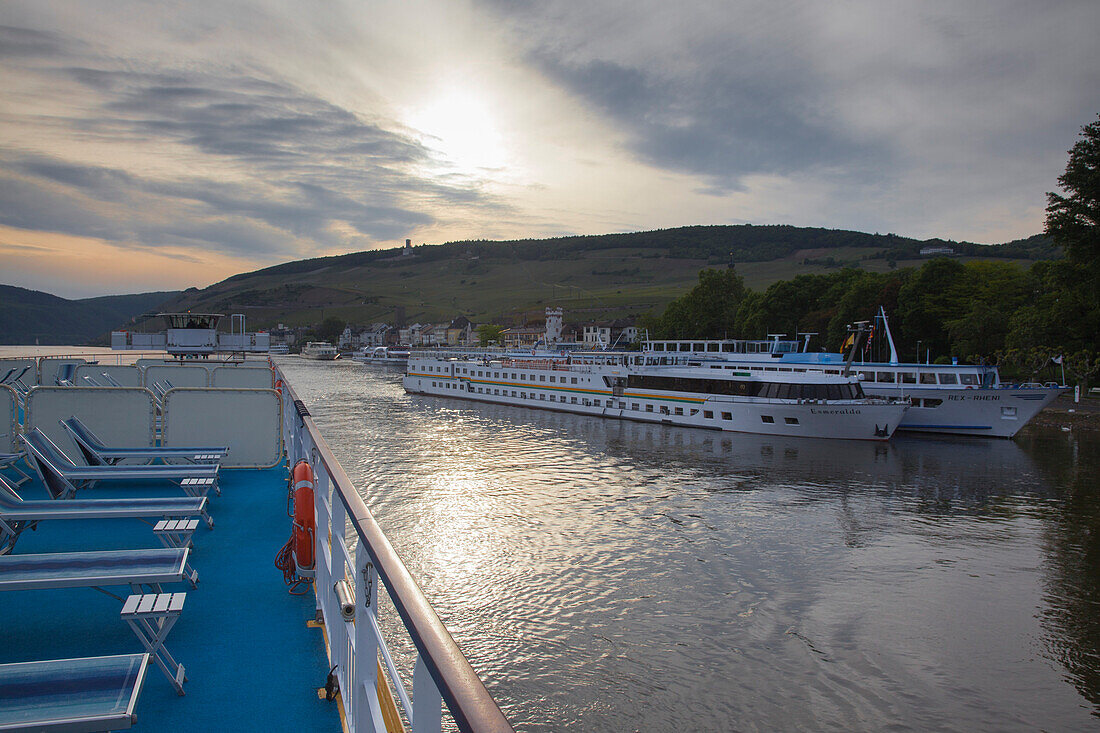Deck von Flusskreuzfahrtschiff MS Bellevue auf dem Rhein und weitere Schiffe am Anleger in der Abenddämmerung, Rüdesheim am Rhein, Hessen, Deutschland, Europa