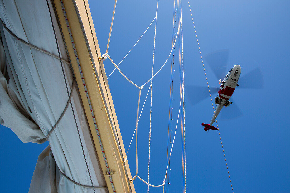 Man lowers himself from Swedish Sjöfartsverket rescue helicopter during rescue exercise on sailing cruise ship Star Flyer (Star Clippers Cruises), near Visby, Gotland, Sweden