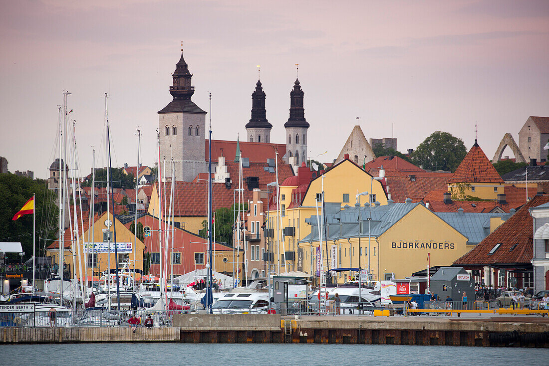 Segelboote im Jachthafen, bunte Gebäude und die Türme des Domskyrkan Dom in der Abenddämmerung, Visby, Gotland, Schweden, Europa
