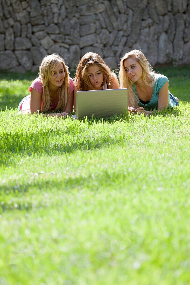 Gruppe von Teenagern mit Laptop im Garten