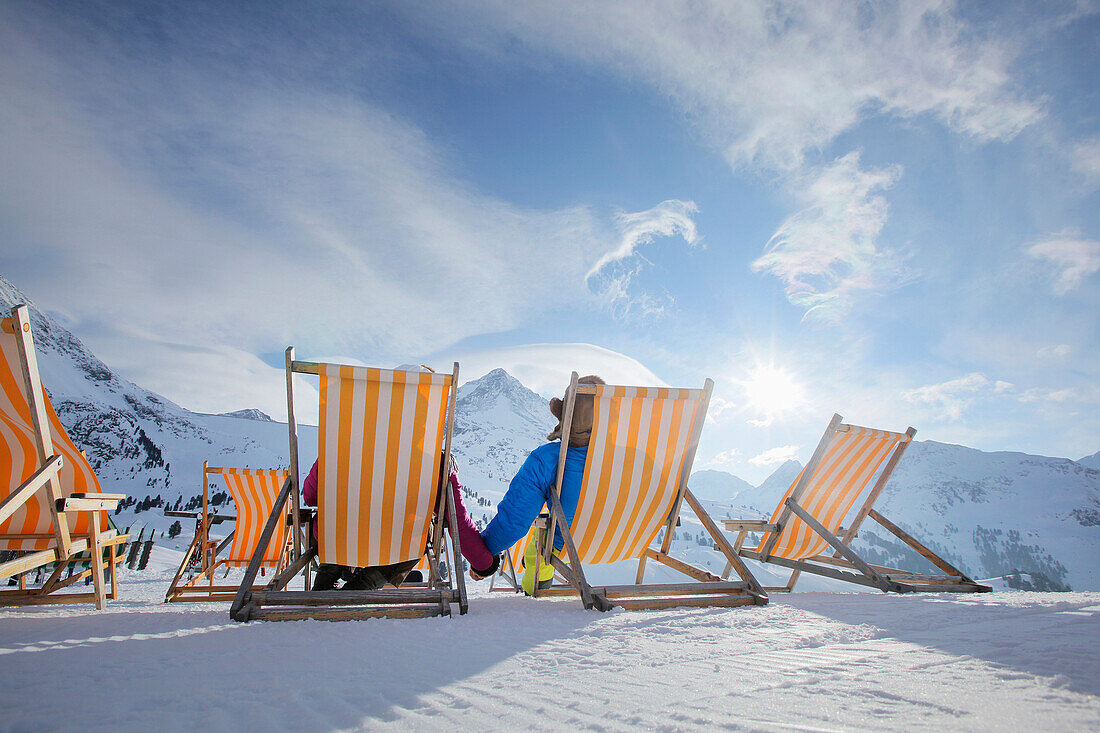 Couple sitting in deckchairs in snow, Kuehtai, Tyrol, Austria