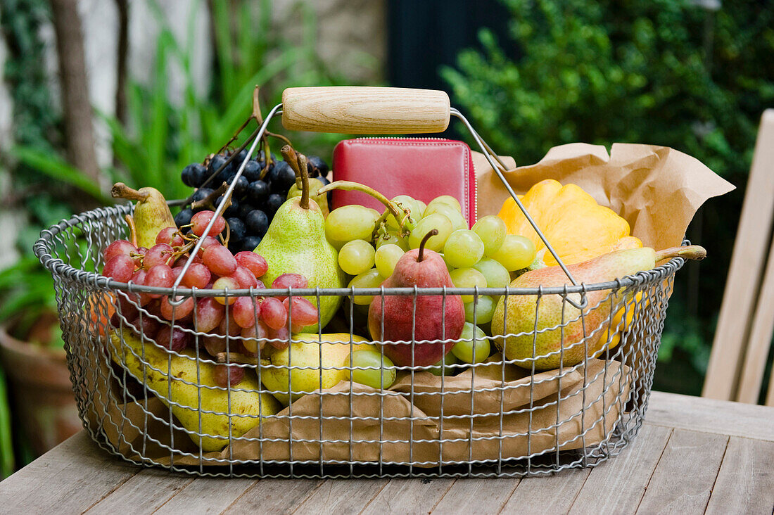Shopping basket full of fruit on a table in the garden, Fruit, Bavaria, Germany