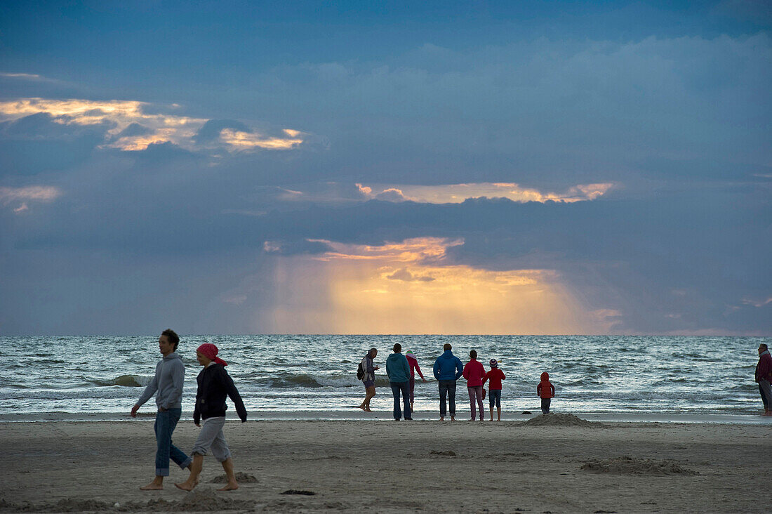 Menschen am Strand bei Sonnenuntergang, St. Peter-Ording, Halbinsel Eiderstedt, Nationalpark Schleswig-Holsteinisches Wattenmeer, Nordfriesland, Schleswig-Holstein, Deutschland, Europa