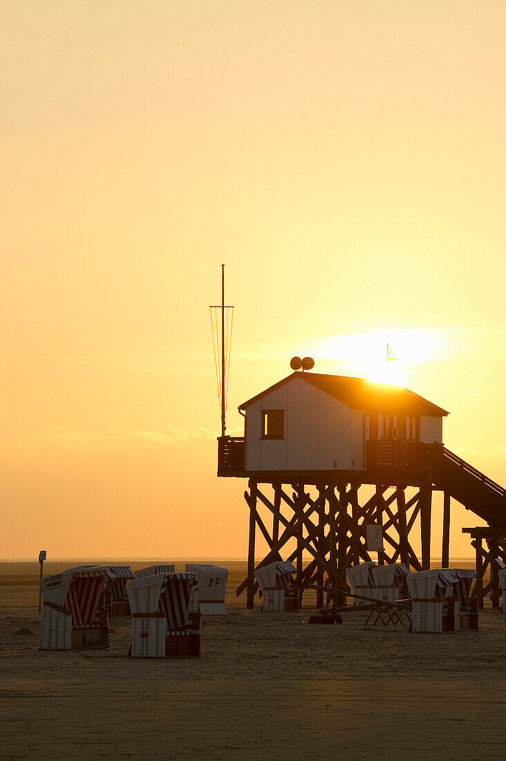 Pfahlbauten am Strand bei Sonnenuntergang, St Peter-Ording, Halbinsel Eiderstedt, Nationalpark Schleswig-Holsteinisches Wattenmeer, Nordfriesland, Schleswig-Holstein, Deutschland, Europa