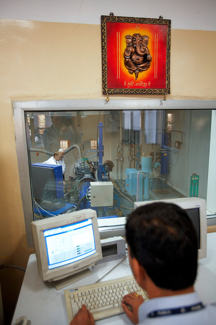 Ingenieur überwacht Lkw-Motor-Teststand unter Abbild der hinduistischen Gottheit Ganesha, MAN Force Trucks Private Limited, Pune, Maharashtra, Indien