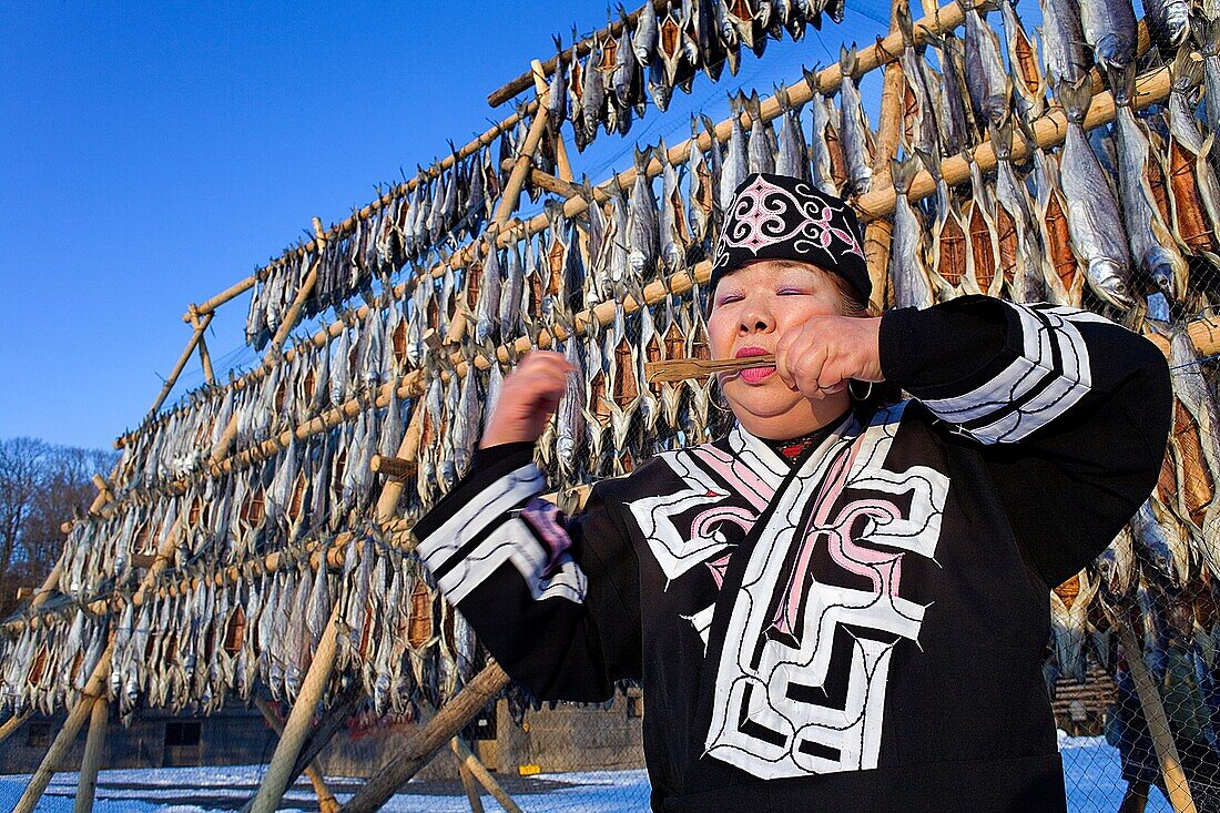 Ainu woman playing a traditional instrument in Ainu village museum,Shiraoi Poroto Kotan,Shiraoi,Hokkaido,Japan