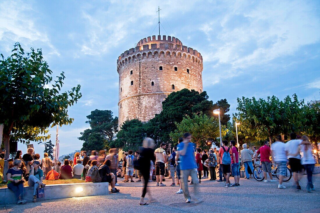 a busy evening at the illuminated white tower, symbol of the town of Thessaloniki, Macedonia, Greece