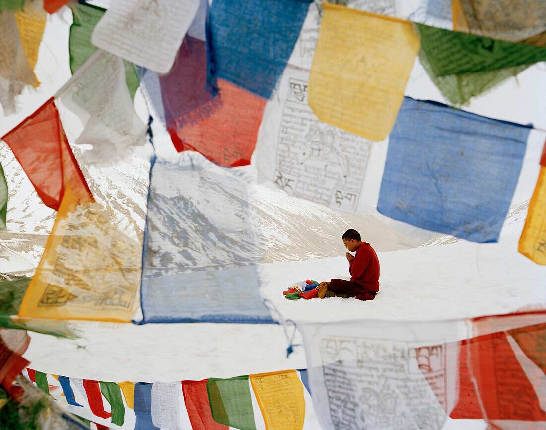 Mönch Wangyal betet auf Khardung La, weiht Gebetsfahnen, 5570 m, höchster befahrbarer Pass und höchste Straße der Welt, nördlich vom Leh, Ladakh, Jammu und Kashmir, Indien