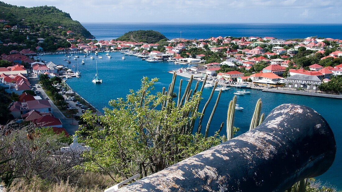 Replica cannon at Fort Gustave above red tin roof buildings in port town of Gustavia St Barts