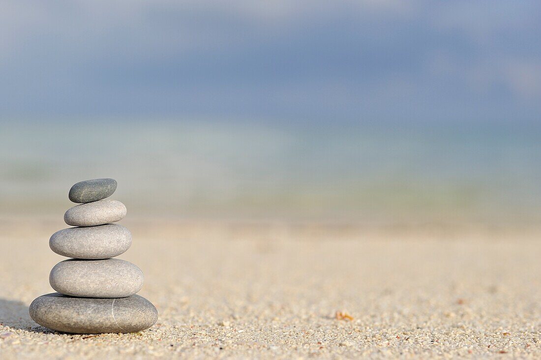 Stack of pebbles on beach, by tropical sea