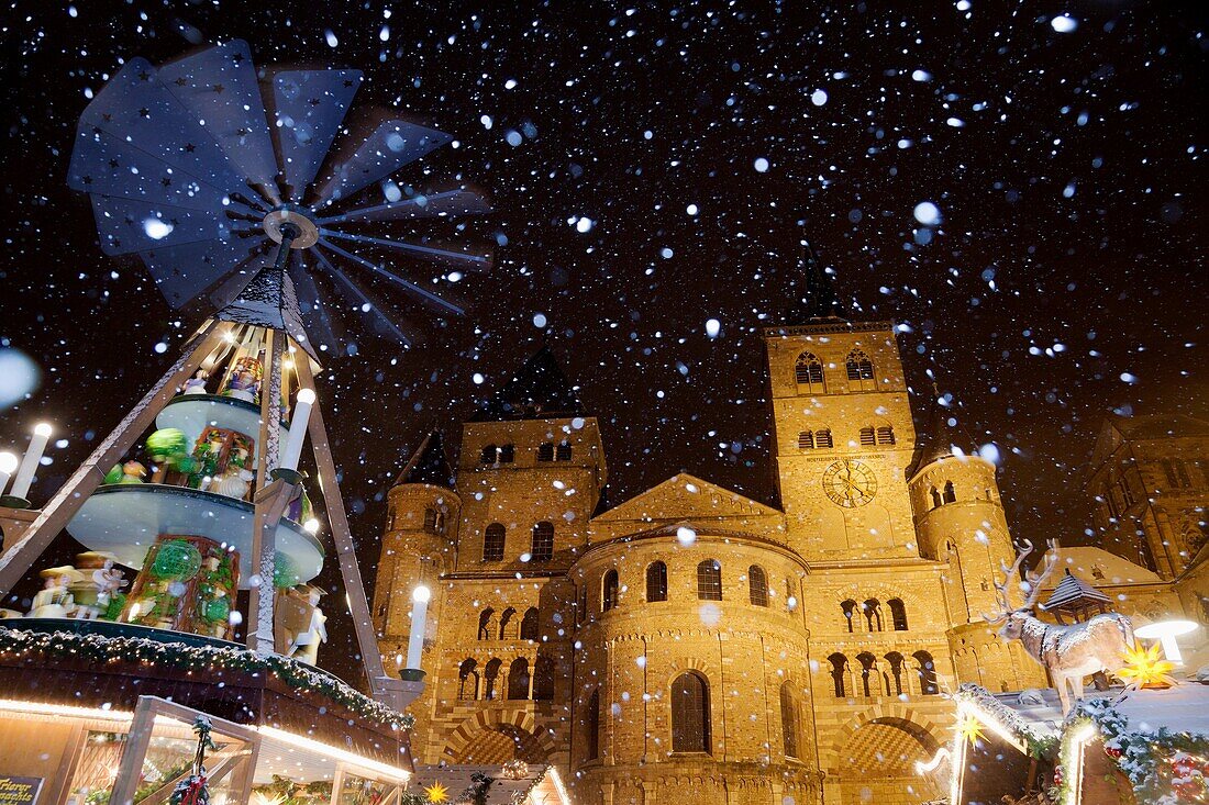Cathedral of Trier and Chistmas market with Christmas pyramid while snowfall at night, Trier, Germany