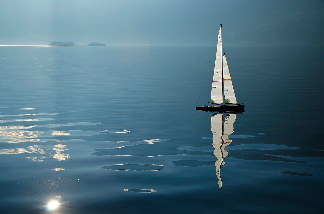 Sailing boat on an alpine lake with islands and reflections
