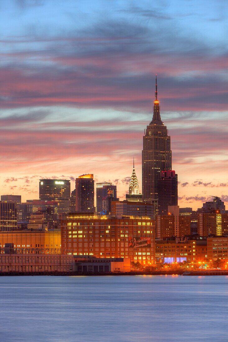 The sky begins to lighten and clouds reflect pre-sunrise color over the Empire State Building and other Manhattan buildings, New York City, New York, USA