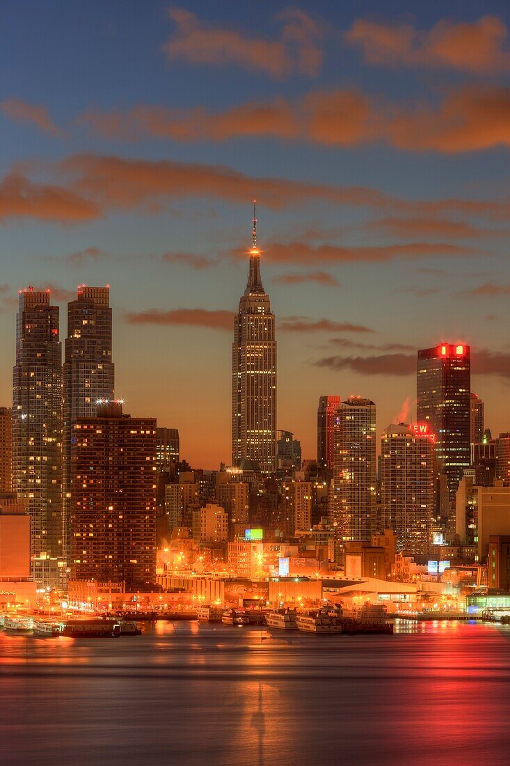 The Empire State Building in New York City during morning twilight as viewed over the Hudson River looking east from New Jersey. The eastern sky and clouds were accented with tinges of orange that began to show in the hour before sunrise.