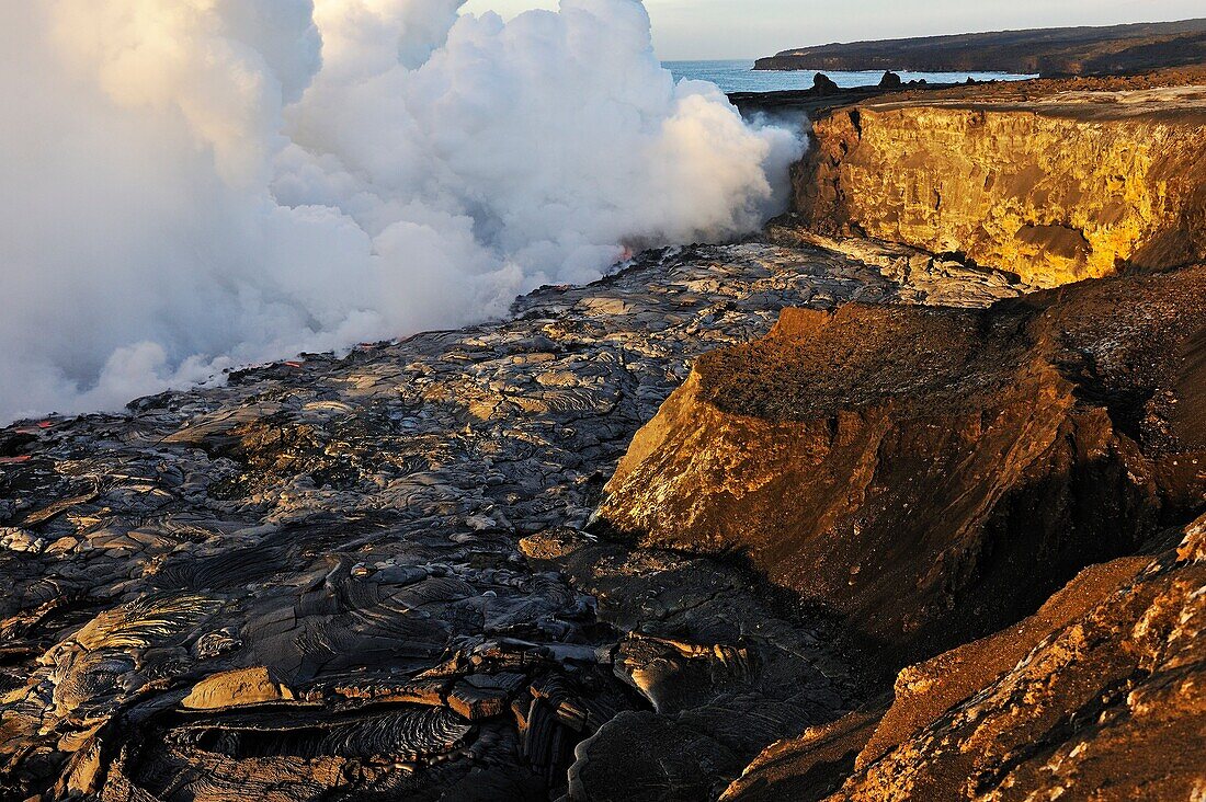 Steam rising off lava flowing into ocean at sunrise, Kilauea Volcano, Big Island, Hawaii Islands, Usa