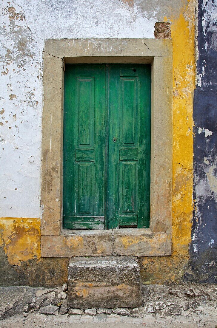 Green Wood Door with Hand Carved Stone against a Texured Wall in the Medieval Village Of Obidos