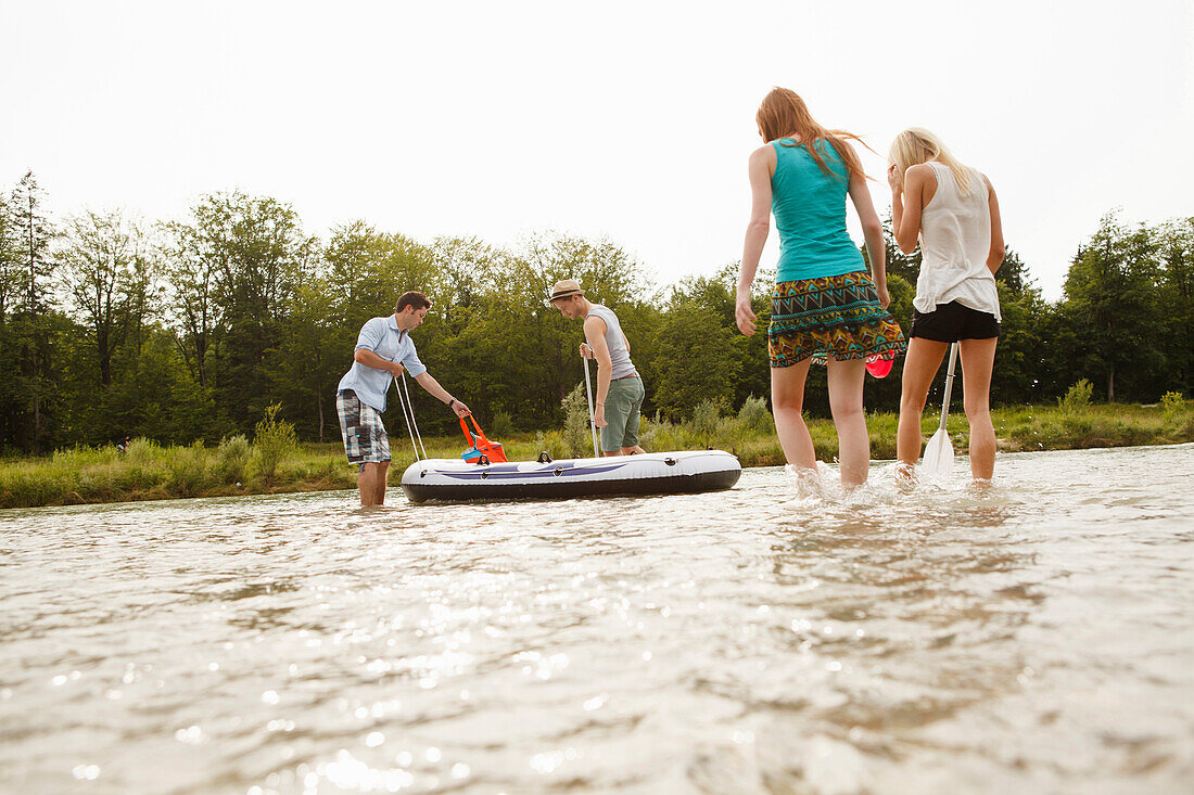 Junge Leute mit einem Schlauchboot an der Isar, München, Bayern, Deutschland