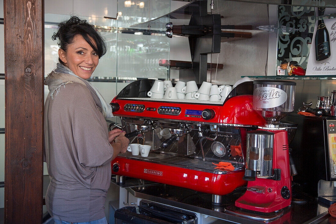 Barista Elisa bereitet einen perfekten Espresso an einer roten Espressomaschine in der schicken Bar Cheri, Chioggia, Venetien, Italien, Europa