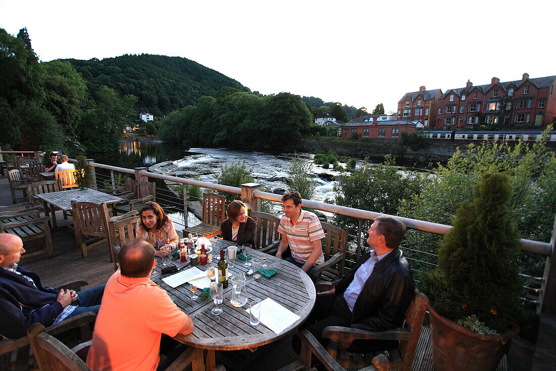 Menschen auf der Terrasse des Restaurants Corn Mill am Fluss Dee in Langollen, Nord Wales, Großbritannien, Europa