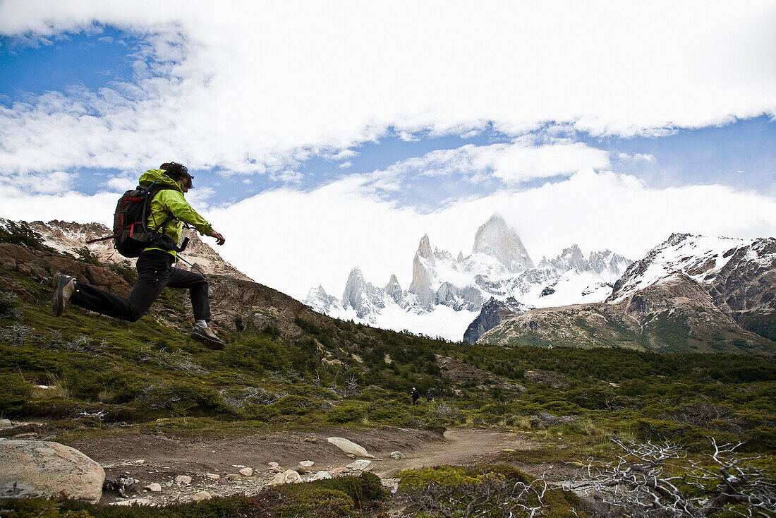 Wanderer springt über Steine am Fitz Roy Massiv, El Chalten, Patagonien, Argentinien