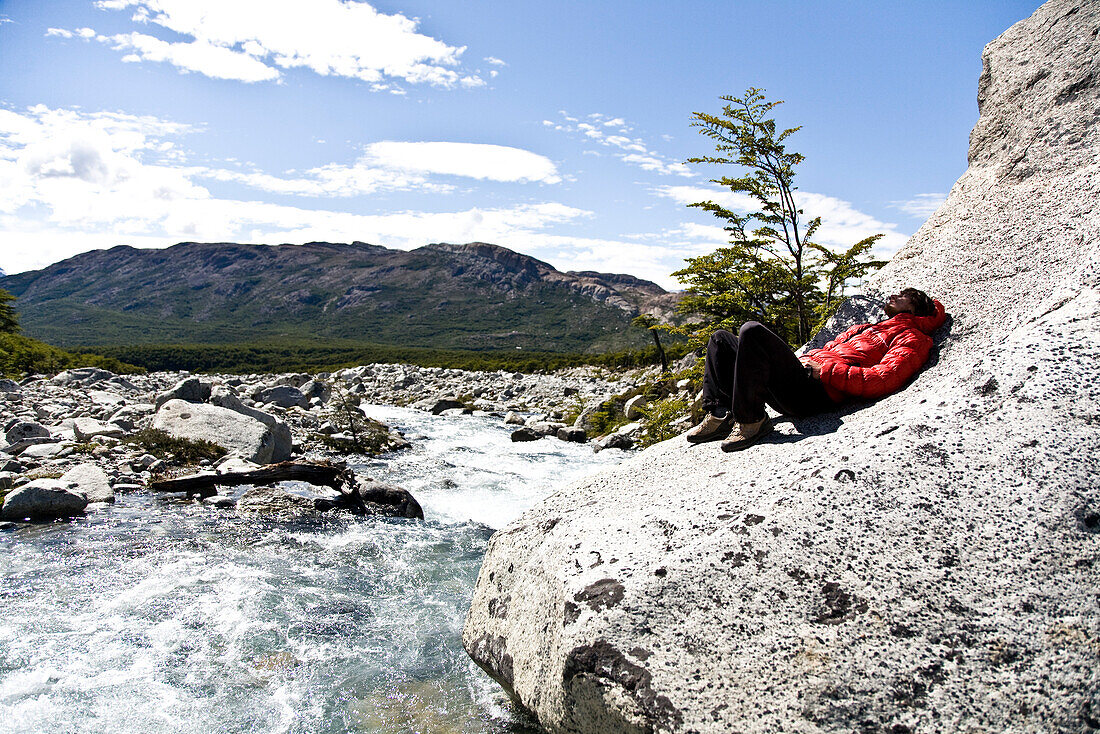 A man resting beside a glacial stream, Fitz Roy, El Chalten, Patagonia, Argentina