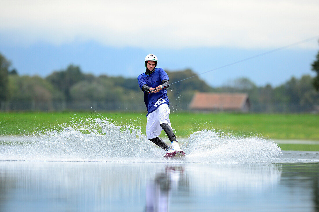 Young man surfing on wakeboard, wakeboarding, lake Neubeurer See, Neubeuern, Rosenheim, Upper Bavaria, Bavaria, Germany