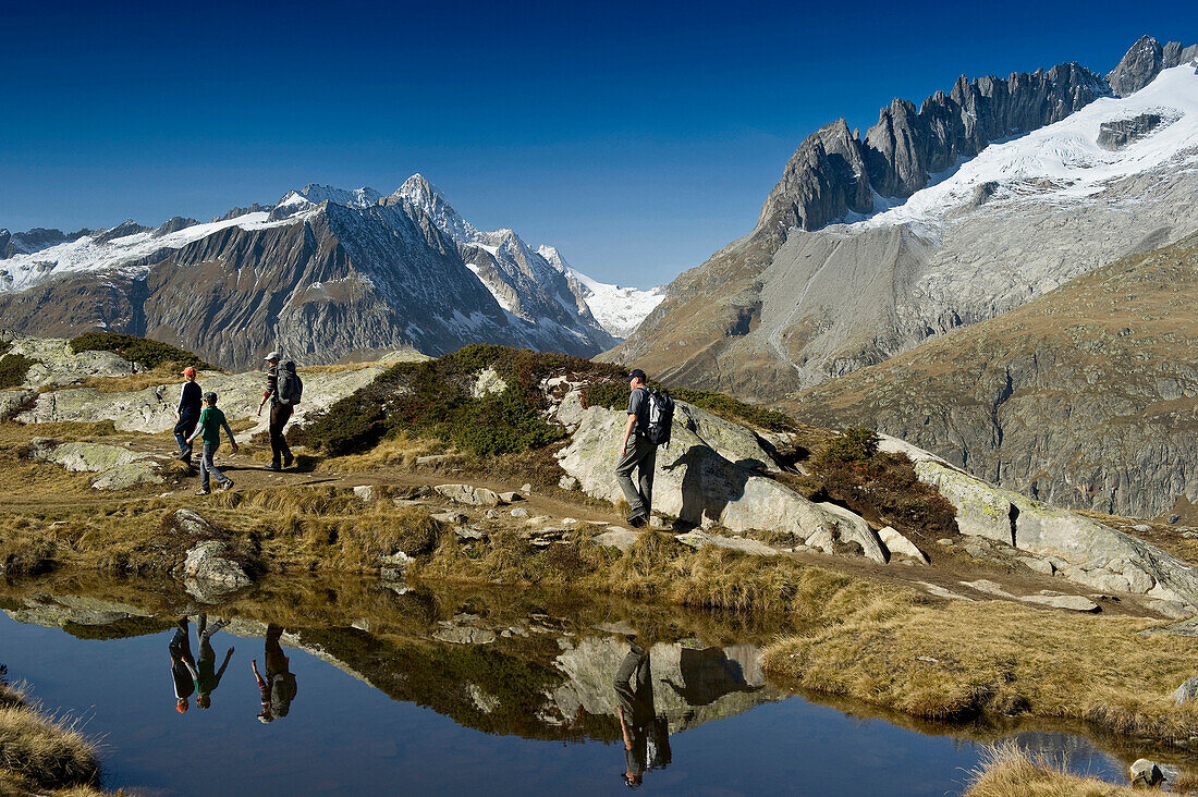 Hiking family at lake Bettmersee, Bettmeralp, in the background Bernese Oberland, Canton of Valais, Switzerland, Europe