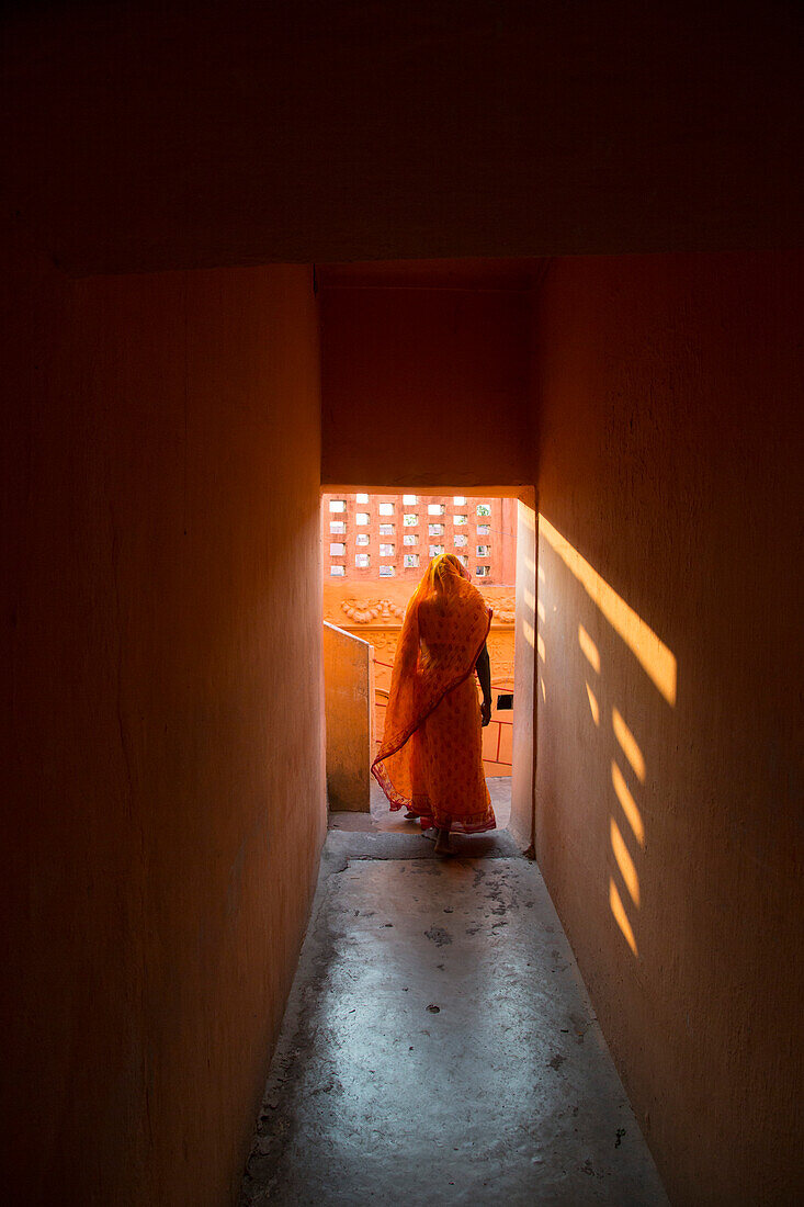 Frau in orangefarbenen Gewand in Gang von Shiva Tempel am Fluss Ganges, Sultanganj, Bihar, Indien